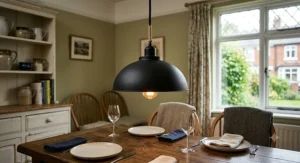 Matt black pendant ceiling light hanging low over a wooden dining table in a British home.