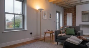 A Scandinavian-inspired light oak and white metal uplighter floor lamp creating a welcoming atmosphere in a bright living room.