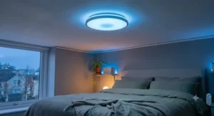 Dimmable colour changing ceiling light with remote control set to a calming blue hue in a cozy bedroom