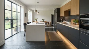 Cool white plinth lights for kitchen contrasting with dark grey slate floor tiles in a newly renovated suburban family home.